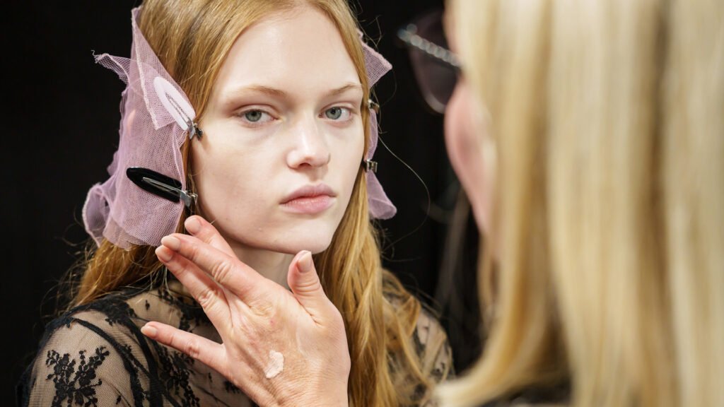 Woman applying face lotion to model backstage at Sacai spring 2025 fashion show