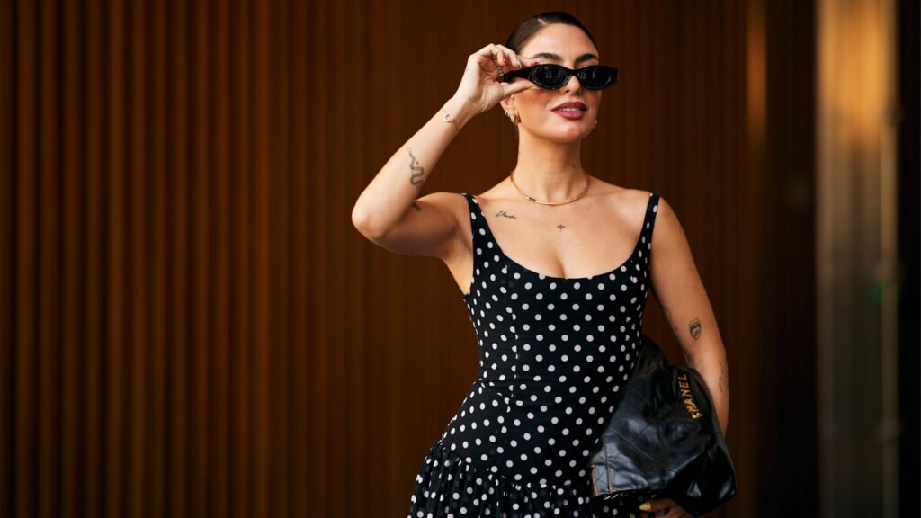 33 Affordable Designer Deals at Nordstrom’s Anniversary Sale 2025 A woman at Paris Fashion Week wearing a black and white polka dot dress, black sunglasses, and black Chanel handbag.