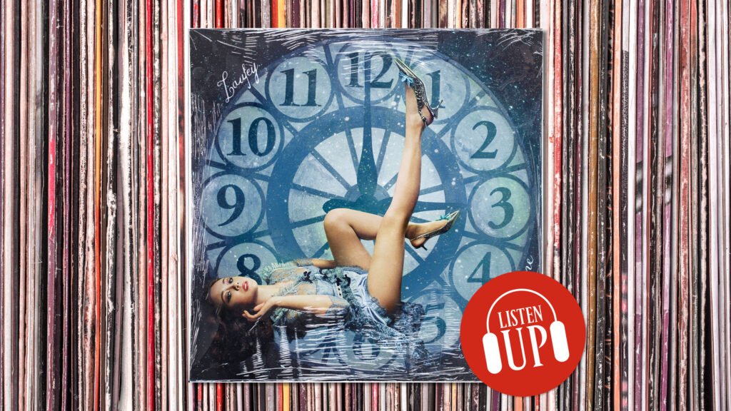 an image of laufey's album cover for a matter of time featuring her lying on a clock imposed over a stack of records