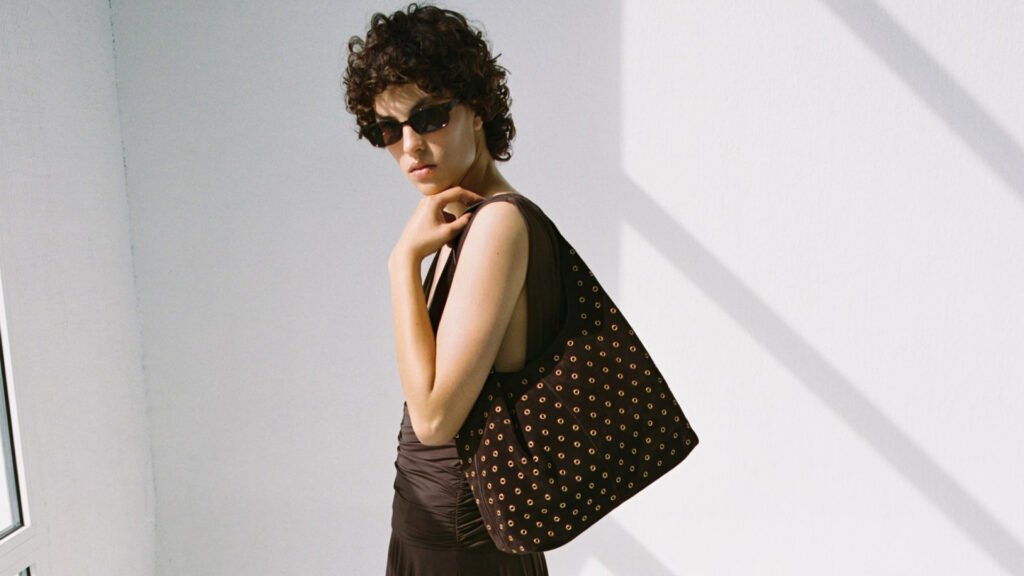 26 Affordable Fall Bags Under $250 to Shop For The New Season Mango model wearing the Suede Shopper Bag With Eyelets over shoulder and sunglasses