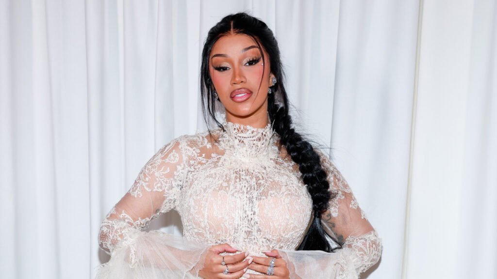 A woman with a fishtail braid hairstyle wearing a sheer, white lace top