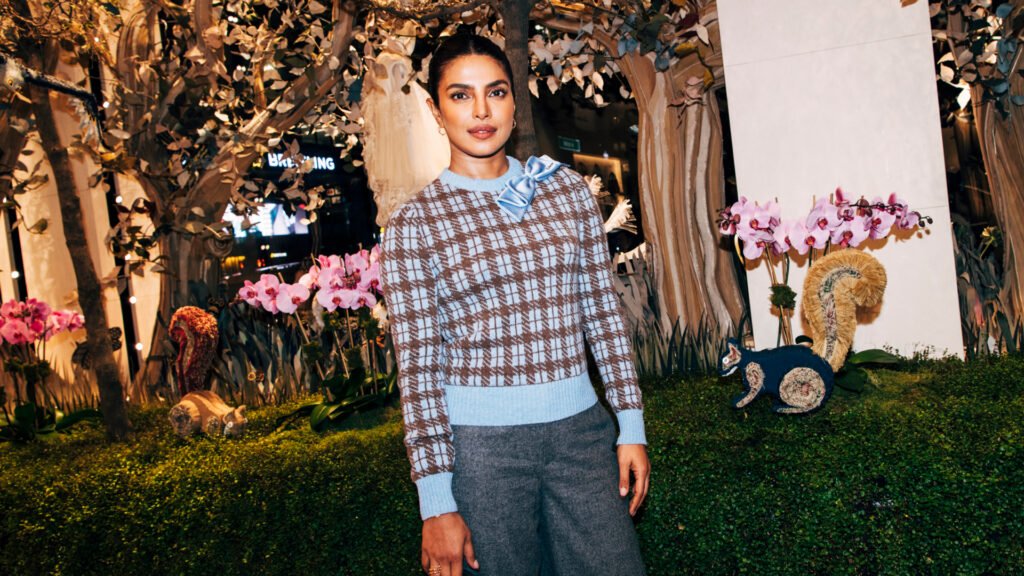 Woman wearing a checkered sweater with a slicked updo hairstyle smiling at the camera